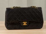 a black chanel bag sitting on top of a wooden table