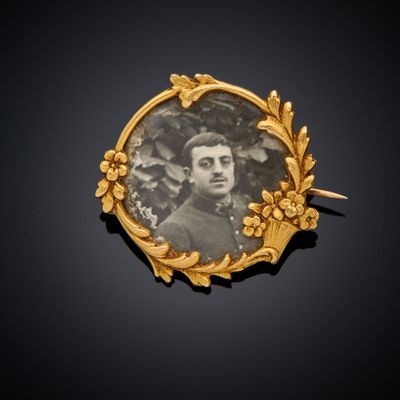 une photo ancienne représentant un homme, dans un cadre doré orné de fleurs