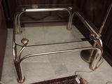 une table basse en verre avec un cadre en métal et un plateau en verre