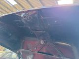 a rusted car inside of a garage with its hood open