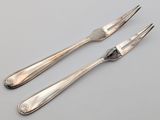 two forks and a knife on a table with a gray background