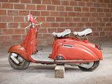 a red scooter that is parked in front of a brick wall