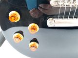 a close up of a black guitar with orange knobs