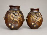 deux vases marron ornés de motifs à la feuille d'or, posés sur une table