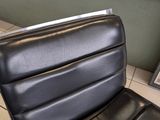 a black leather chair and ottoman in the corner of a room