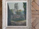 painting of a church in a white frame on a wooden floor