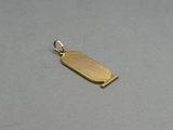 a small gold plated pendant with a rectangular shape on a gray surface