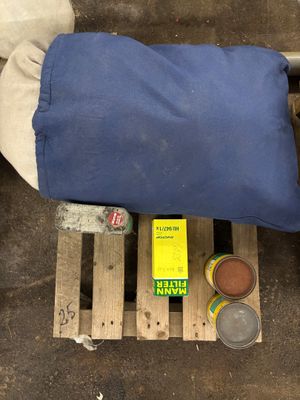 un sac bleu posé sur une palette, à côté d'une bouteille de bière