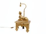 une statue en or posée sur une table sur laquelle se trouve une lampe