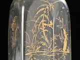 a clear glass bottle with a gold design on it