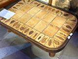 une table en bois avec un plateau en carrelage sur lequel est posé un tableau