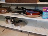 une étagère sur laquelle sont posés des casseroles et des poêles, dans la cuisine