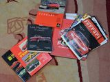 plusieurs livres posés sur un tapis, avec une voiture rouge en arrière-plan