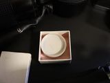 a white cup sitting on a table next to a camera