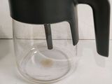 a glass coffee pot with a black handle on a counter