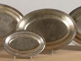 three silver plates are sitting on a table with a white background