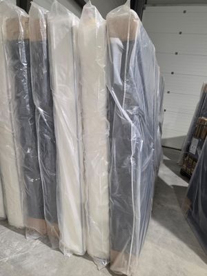 de nombreux rouleaux de matelas emballés dans du plastique dans un entrepôt