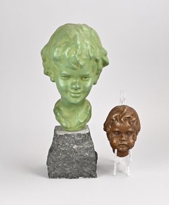une sculpture représentant un garçon et un buste de garçon posé sur un rocher