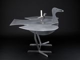 a metal sculpture of a bird with a candle on it