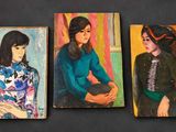 three paintings of women are displayed on a black surface