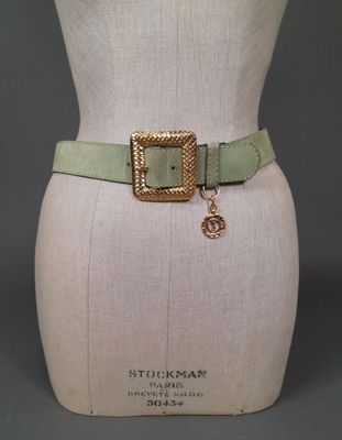 a close up of a mannequin torso wearing a green belt with a gold buckle