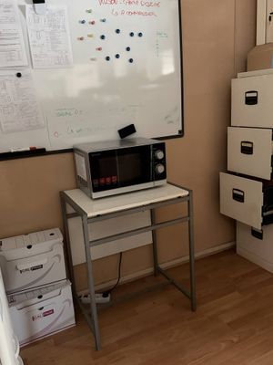 an image of a room with a white board on the wall and a microwave on the table