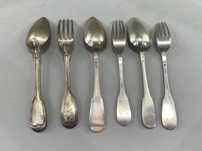 six spoons and a fork are lined up on a table