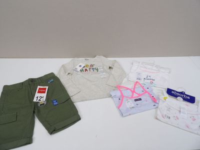 une table blanche sur laquelle sont posés des vêtements et une paire de ciseaux