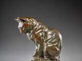 a bronze statue of a cat sitting on a rock
