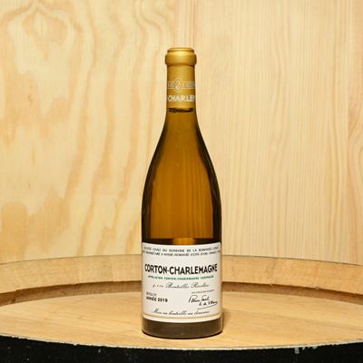 a bottle of wine sitting on top of a wooden barrel