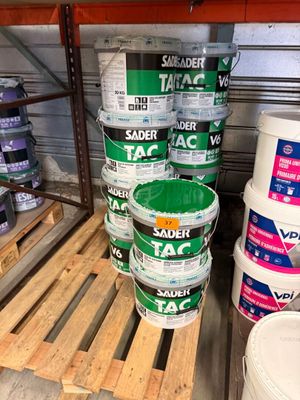 Plusieurs seaux de peinture sont empilés sur une palette dans un entrepôt