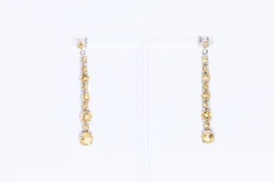 boucles d'oreilles en or et en argent posées sur un présentoir blanc, sur fond blanc
