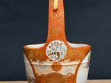 an orange and white vase sitting on top of a wooden table