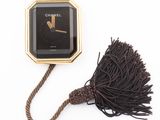 a black and gold clock with a tassel attached to it