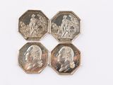 quatre pièces de monnaie britanniques différentes empilées les unes sur les autres sur une surface blanche