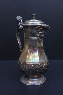 a silver coffee pot on a table with a black background