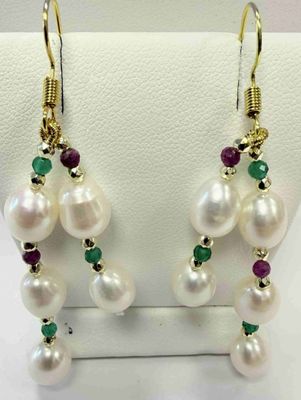 white pearls and emerald earrings on display in a display case
