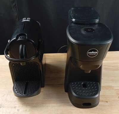 two coffee machines sitting on a table next to each other