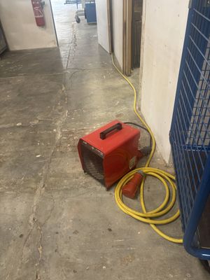 un radiateur rouge et un tuyau jaune posés par terre