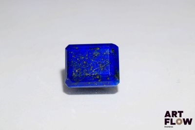 un gros plan d'une pierre bleue carrée posée sur une surface blanche