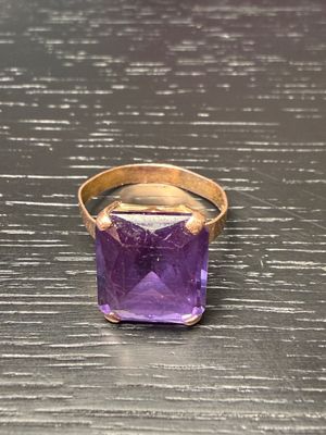 an image of a purple stone ring sitting on top of a wooden table