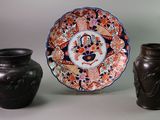 three vases and a plate sitting on a table