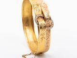 a close up of a gold bracelet with a chain on a white background