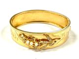 gold bangle with flowers and pearls on it on a white surface