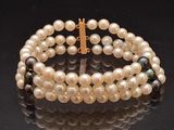 a bracelet with pearls and a gold clasp on a black surface