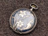 un gros plan d'une montre de poche ornée d'un motif floral