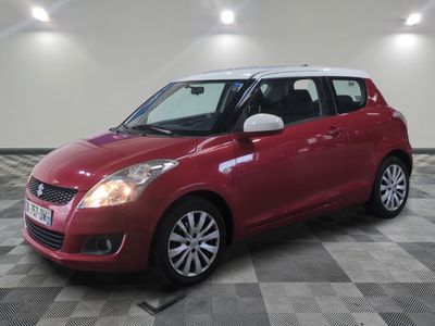 a red suzuki swift is parked on a checkered floor