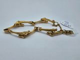 une paire de bracelets en or posés sur une surface blanche