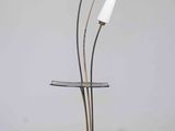 a three light floor lamp with a glass top and a metal base