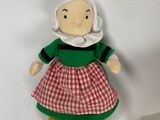a stuffed doll of a woman in a red and green dress next to a box of donuts